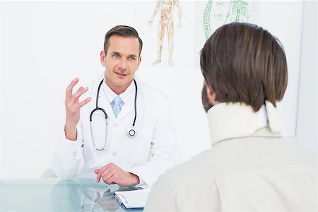 simsearch:400-07269643,k - Friendly male doctor in communication with patient at desk in medical office Fotografie stock - Microstock e Abbonamento, Codice: 400-07269165