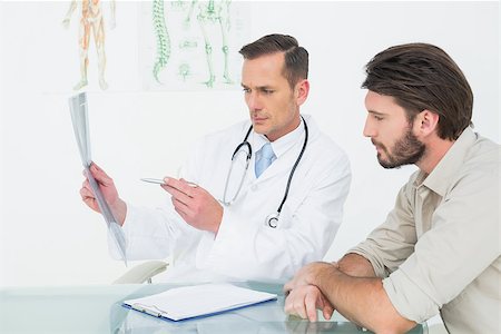 Male doctor explaining spine x-ray to patient in the medical office Stockbilder - Microstock & Abonnement, Bildnummer: 400-07269187