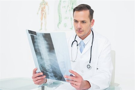 simsearch:400-07269643,k - Concentrated male doctor looking at x-ray picture in the medical office Fotografie stock - Microstock e Abbonamento, Codice: 400-07269247