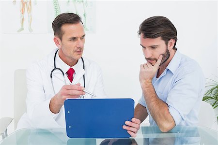 simsearch:400-07269643,k - Male doctor discussing reports with patient at desk in medical office Fotografie stock - Microstock e Abbonamento, Codice: 400-07269327