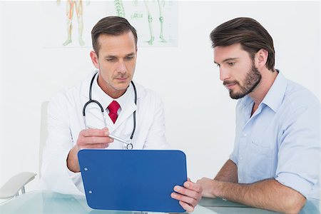 simsearch:400-07269643,k - Male doctor discussing reports with patient at desk in medical office Fotografie stock - Microstock e Abbonamento, Codice: 400-07269320