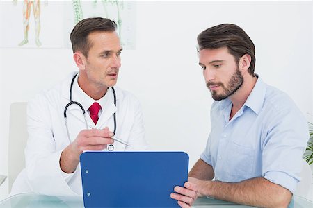 simsearch:400-07269643,k - Male doctor discussing reports with patient at desk in medical office Fotografie stock - Microstock e Abbonamento, Codice: 400-07269323