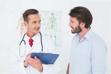 simsearch:400-07269643,k - Male doctor discussing reports with patient in the medical office Fotografie stock - Microstock e Abbonamento, Codice: 400-07269343