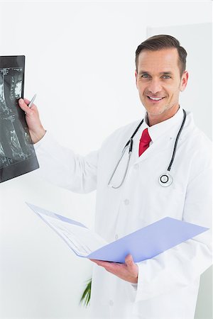 simsearch:400-07269643,k - Portrait of a smiling male doctor examining x-ray over white background Fotografie stock - Microstock e Abbonamento, Codice: 400-07269362