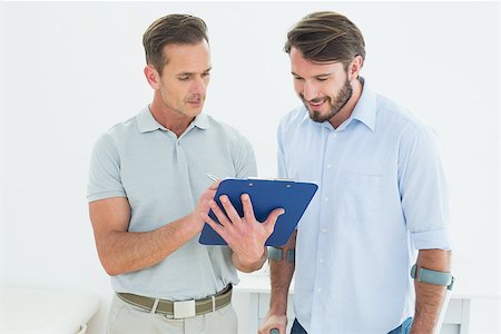 simsearch:400-07269643,k - Male therapist discussing reports with a disabled patient in the medical office Fotografie stock - Microstock e Abbonamento, Codice: 400-07269420