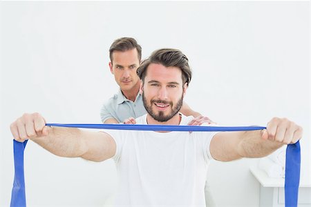 simsearch:400-07232187,k - Male therapist assisting young man with exercises in the medical office Foto de stock - Royalty-Free Super Valor e Assinatura, Número: 400-07269470