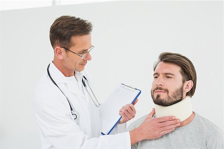 simsearch:400-07269643,k - Male doctor examining a patient's sprained neck over white background Fotografie stock - Microstock e Abbonamento, Codice: 400-07269634