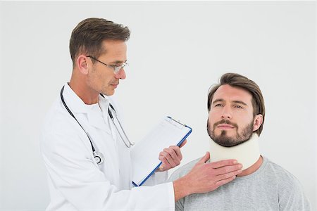 simsearch:400-07269643,k - Male doctor examining a patient's sprained neck over white background Fotografie stock - Microstock e Abbonamento, Codice: 400-07269637