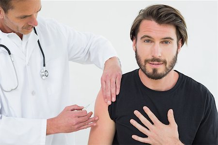 simsearch:400-07269643,k - Male doctor injecting a young male patient's arm over white background Fotografie stock - Microstock e Abbonamento, Codice: 400-07269676