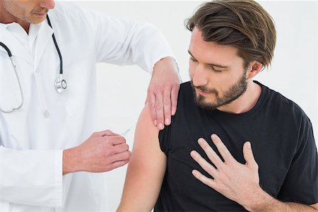 simsearch:400-07269643,k - Male doctor injecting a young male patient's arm over white background Fotografie stock - Microstock e Abbonamento, Codice: 400-07269673