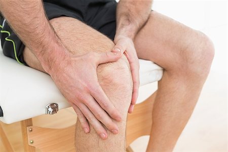 Close-up mid section of a young man with his hands on a painful knee while sitting on examination table Stock Photo - Budget Royalty-Free & Subscription, Code: 400-07269705
