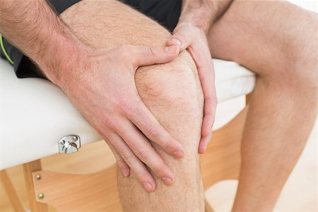 Close-up mid section of a young man with his hands on a painful knee while sitting on examination table Stock Photo - Budget Royalty-Free & Subscription, Code: 400-07269703
