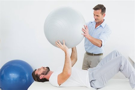 simsearch:400-07232187,k - Physical therapist assisting young man with yoga ball in the gym at hospital Foto de stock - Royalty-Free Super Valor e Assinatura, Número: 400-07269825