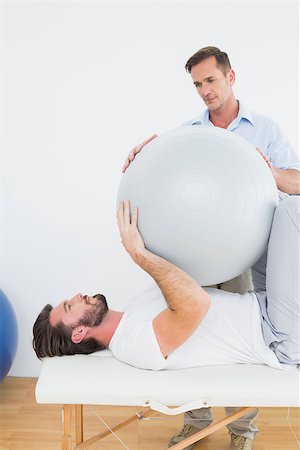 simsearch:400-07232187,k - Physical therapist assisting young man with yoga ball in the gym at hospital Foto de stock - Royalty-Free Super Valor e Assinatura, Número: 400-07269828