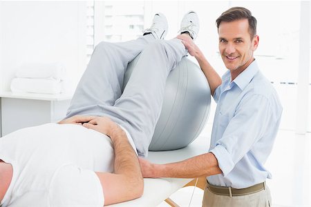 simsearch:400-07232187,k - Physical therapist assisting young man with yoga ball in the gym at hospital Foto de stock - Royalty-Free Super Valor e Assinatura, Número: 400-07269822