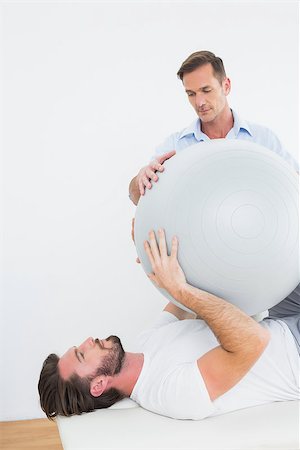 simsearch:400-07232187,k - Physical therapist assisting young man with yoga ball in the gym at hospital Foto de stock - Royalty-Free Super Valor e Assinatura, Número: 400-07269830