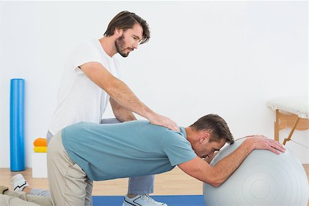 simsearch:400-07232187,k - Physical therapist assisting young man with yoga ball in the gym at hospital Foto de stock - Royalty-Free Super Valor e Assinatura, Número: 400-07269856