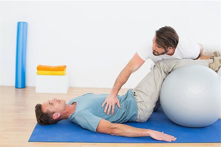 simsearch:400-07232187,k - Physical therapist assisting young man with yoga ball in the gym at hospital Foto de stock - Royalty-Free Super Valor e Assinatura, Número: 400-07269859