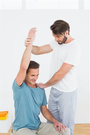 simsearch:400-07232187,k - Physical therapist assisting young man with stretching exercises in the gym hospital Foto de stock - Royalty-Free Super Valor e Assinatura, Número: 400-07269850