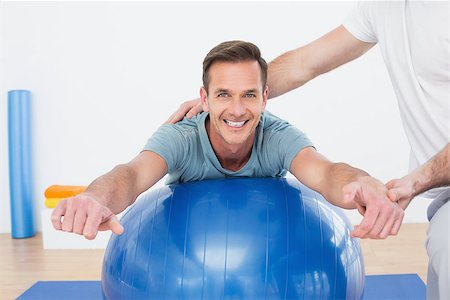 simsearch:400-07232187,k - Physical therapist assisting young man with yoga ball in the gym at hospital Foto de stock - Royalty-Free Super Valor e Assinatura, Número: 400-07269867