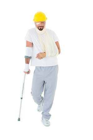 simsearch:400-04255649,k - Full length of a young man in hard hat with broken hand and crutch over  white background Foto de stock - Royalty-Free Super Valor e Assinatura, Número: 400-07269934
