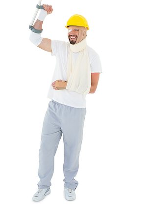 simsearch:400-04255649,k - Full length of a young man in hard hat with broken hand and crutch over  white background Foto de stock - Royalty-Free Super Valor e Assinatura, Número: 400-07269940