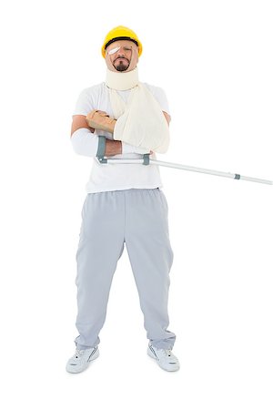 simsearch:400-04255649,k - Full length of a young man in hard hat with broken hand and crutch over  white background Foto de stock - Royalty-Free Super Valor e Assinatura, Número: 400-07269943