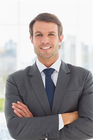 simsearch:400-07275828,k - Portrait of a young businessman with arms crossed standing over blurred background outdoors Photographie de stock - Aubaine LD & Abonnement, Code: 400-07274414