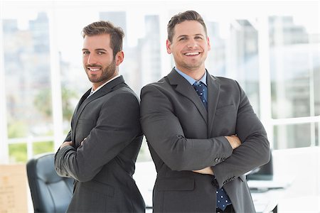 simsearch:400-07275828,k - Portrait of two young businessmen standing with arms crossed in a bright office Photographie de stock - Aubaine LD & Abonnement, Code: 400-07274445
