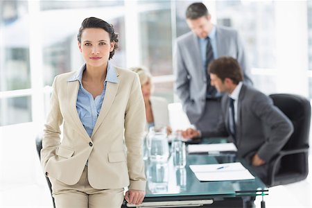 simsearch:400-07274497,k - Portrait of a young businesswoman with colleagues discussing in background at a bright office Stock Photo - Budget Royalty-Free & Subscription, Code: 400-07274486