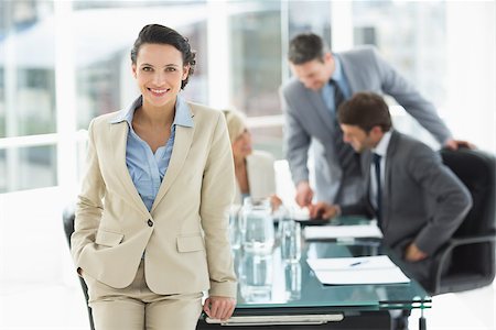 simsearch:400-07274497,k - Portrait of a young businesswoman with colleagues discussing in background at a bright office Stock Photo - Budget Royalty-Free & Subscription, Code: 400-07274487