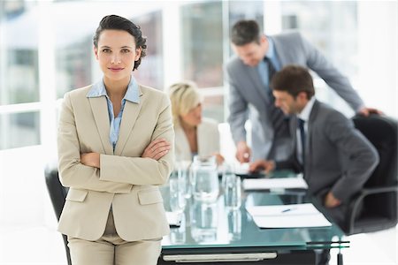 simsearch:400-07274497,k - Portrait of a young businesswoman with colleagues discussing in background at a bright office Stock Photo - Budget Royalty-Free & Subscription, Code: 400-07274488