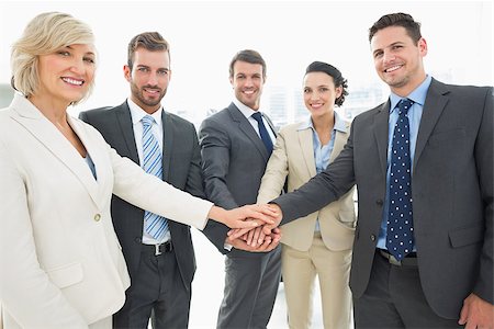 simsearch:400-07274497,k - Portrait of a business team joining hands together in a bright office Stock Photo - Budget Royalty-Free & Subscription, Code: 400-07274499