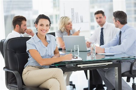 simsearch:400-07274497,k - Young businesswoman with colleagues discussing in background at a bright office Stock Photo - Budget Royalty-Free & Subscription, Code: 400-07274579