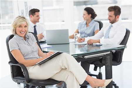 simsearch:400-07274497,k - Young businesswoman with colleagues discussing in background at a bright office Stock Photo - Budget Royalty-Free & Subscription, Code: 400-07274584