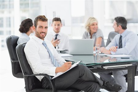 simsearch:400-07274497,k - Young businessman with colleagues discussing in background at a bright office Stock Photo - Budget Royalty-Free & Subscription, Code: 400-07274581