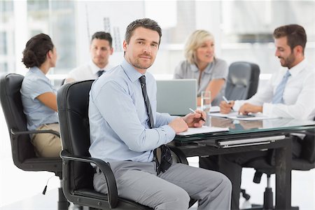 simsearch:400-07274497,k - Young businessman with colleagues discussing in background at a bright office Stock Photo - Budget Royalty-Free & Subscription, Code: 400-07274582