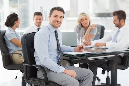 simsearch:400-07274497,k - Young businessman with colleagues discussing in background at a bright office Stock Photo - Budget Royalty-Free & Subscription, Code: 400-07274583