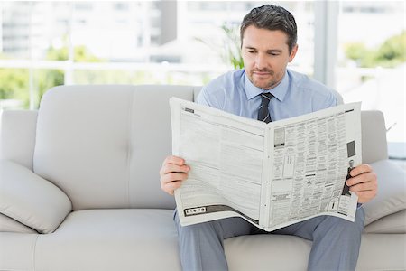 simsearch:400-07274613,k - Well dressed relaxed young man reading newspaper on sofa in the house Stock Photo - Budget Royalty-Free & Subscription, Code: 400-07274609