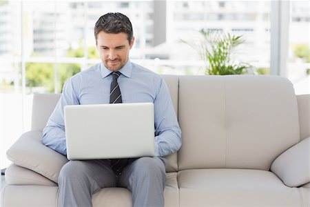 simsearch:400-07274613,k - Well dressed relaxed young man using laptop on sofa in the house Stock Photo - Budget Royalty-Free & Subscription, Code: 400-07274611