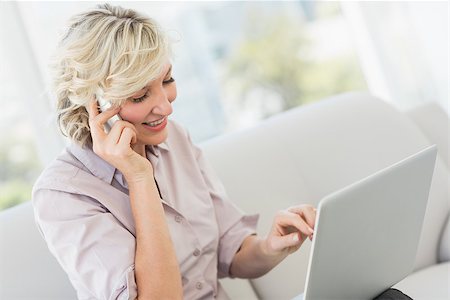 sophisticated home smile - Smiling beautiful businesswoman using mobile phone and laptop at home Stock Photo - Budget Royalty-Free & Subscription, Code: 400-07274653