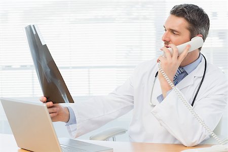 simsearch:400-07275966,k - Serious male doctor examining xray while on call in the medical office Foto de stock - Super Valor sin royalties y Suscripción, Código: 400-07274836