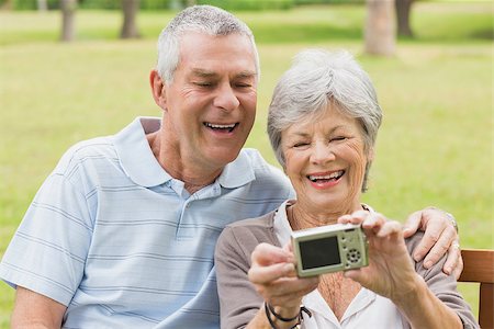 simsearch:400-07274981,k - Cheerful senior couple photographing themselves while sitting on bench at the park Stock Photo - Budget Royalty-Free & Subscription, Code: 400-07274925