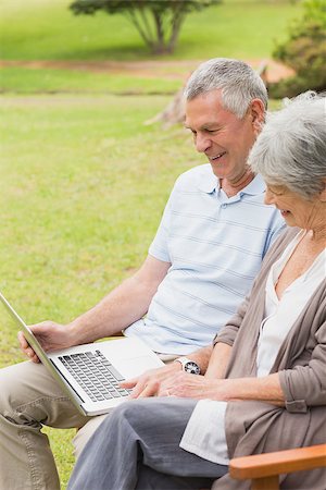 simsearch:400-07275058,k - Smiling senior woman and man using laptop on bench at the park Fotografie stock - Microstock e Abbonamento, Codice: 400-07274930