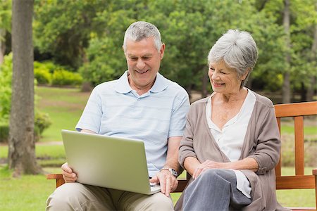 simsearch:400-07275058,k - Smiling senior woman and man using laptop on bench at the park Fotografie stock - Microstock e Abbonamento, Codice: 400-07274931