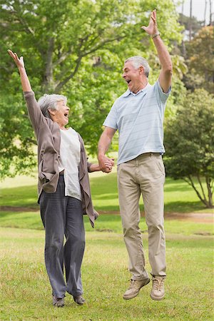 simsearch:400-07275058,k - Full length of active senior couple holding hands and jumping in the park Fotografie stock - Microstock e Abbonamento, Codice: 400-07274940