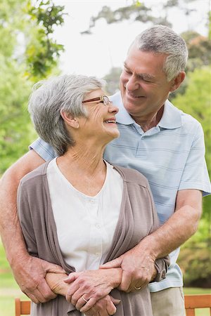 simsearch:400-07275058,k - Happy senior man embracing woman from behind at the park Fotografie stock - Microstock e Abbonamento, Codice: 400-07274973