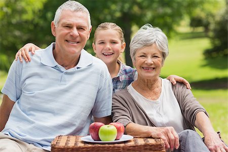 simsearch:400-07275058,k - Portrait of a smiling senior couple and granddaughter sitting with picnic basket at the park Fotografie stock - Microstock e Abbonamento, Codice: 400-07275039