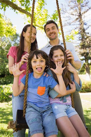 simsearch:400-07275176,k - Happy couple pushing kids on swing in playground Stock Photo - Budget Royalty-Free & Subscription, Code: 400-07275171