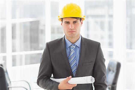 simsearch:400-07275251,k - Serious architect holding blueprints looking at camera in the office Stock Photo - Budget Royalty-Free & Subscription, Code: 400-07275263